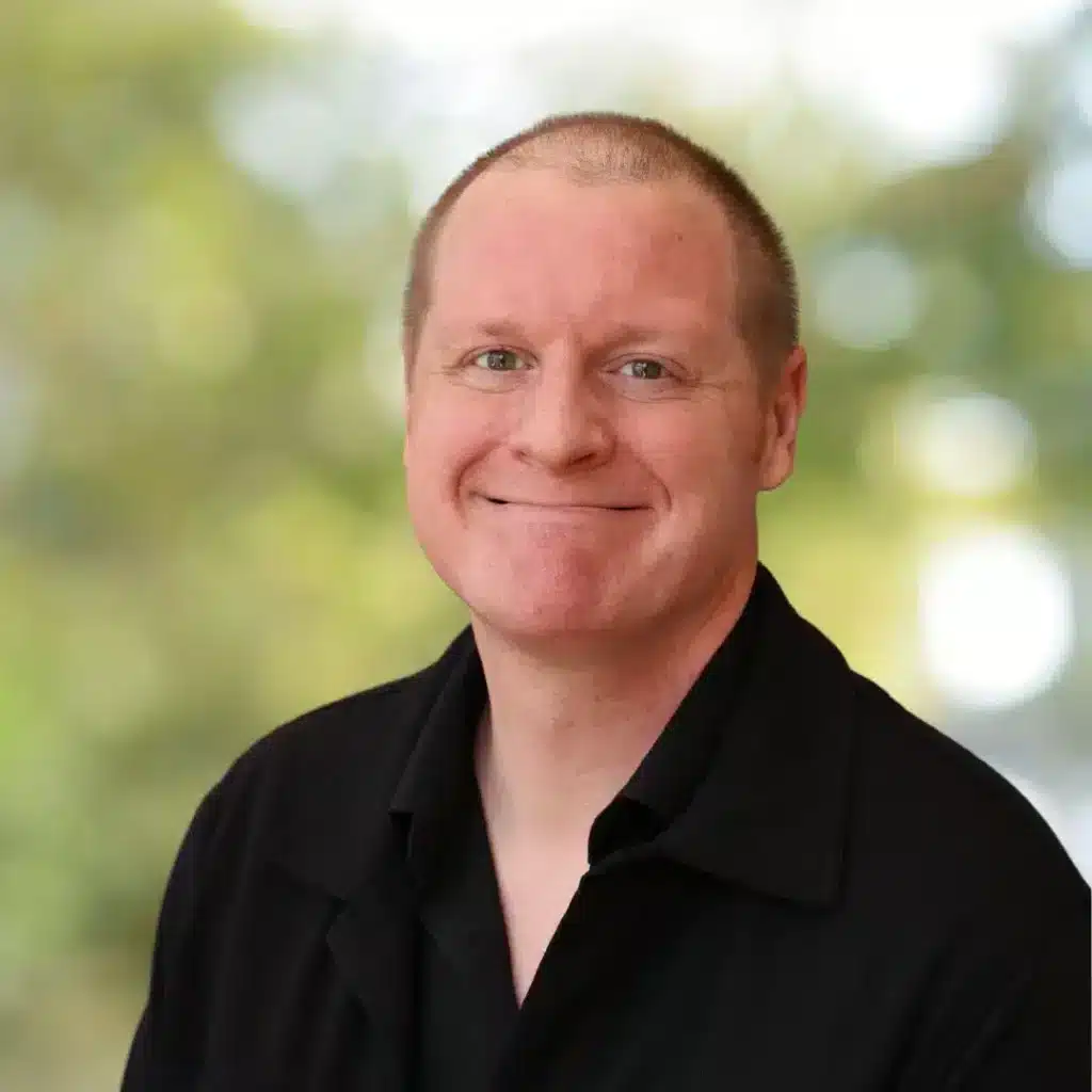 Smiling man in black shirt portrait. Professional headshot of a Caucasian man with short hair and a friendly expression.