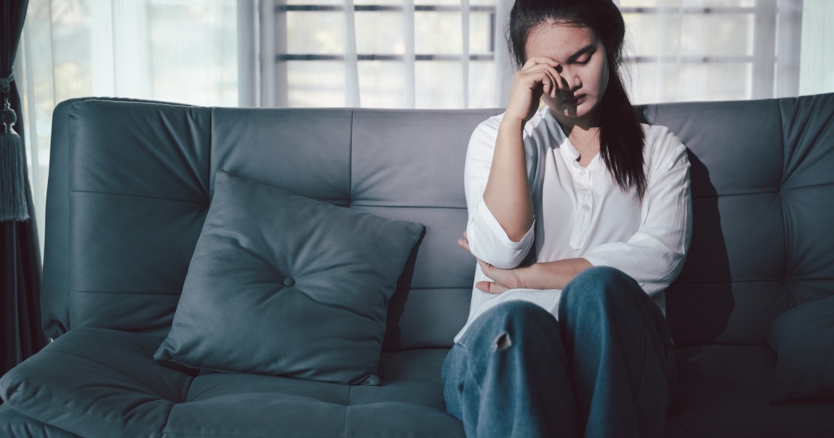 IMAGE - 2026-09-18T160152078 - San Jose Mental Health Woman sitting on a teal couch with a hand on her forehead, looking stressed or sad.
